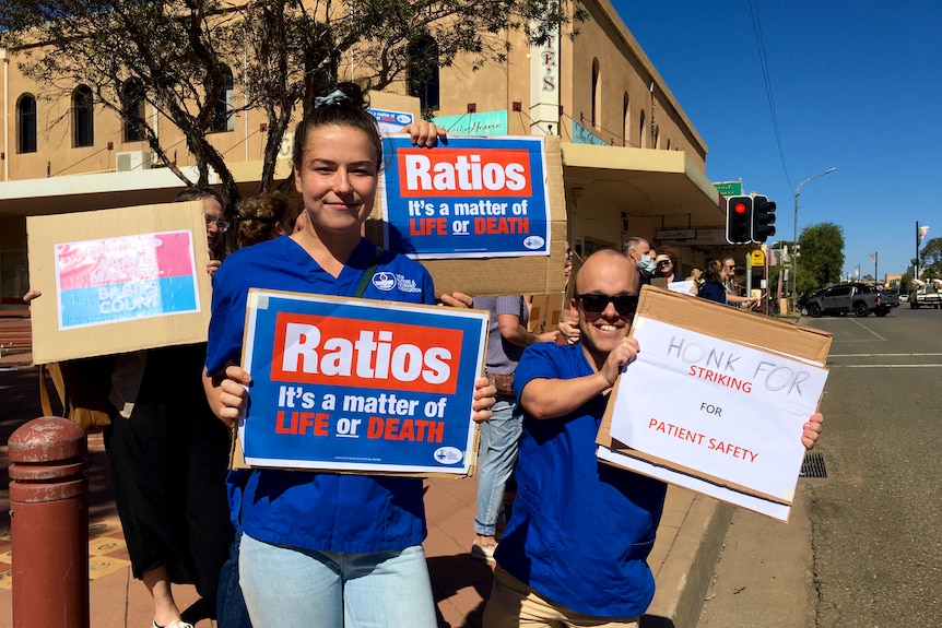 A male and female nurse hold up a sign while on strike in Broken Hill