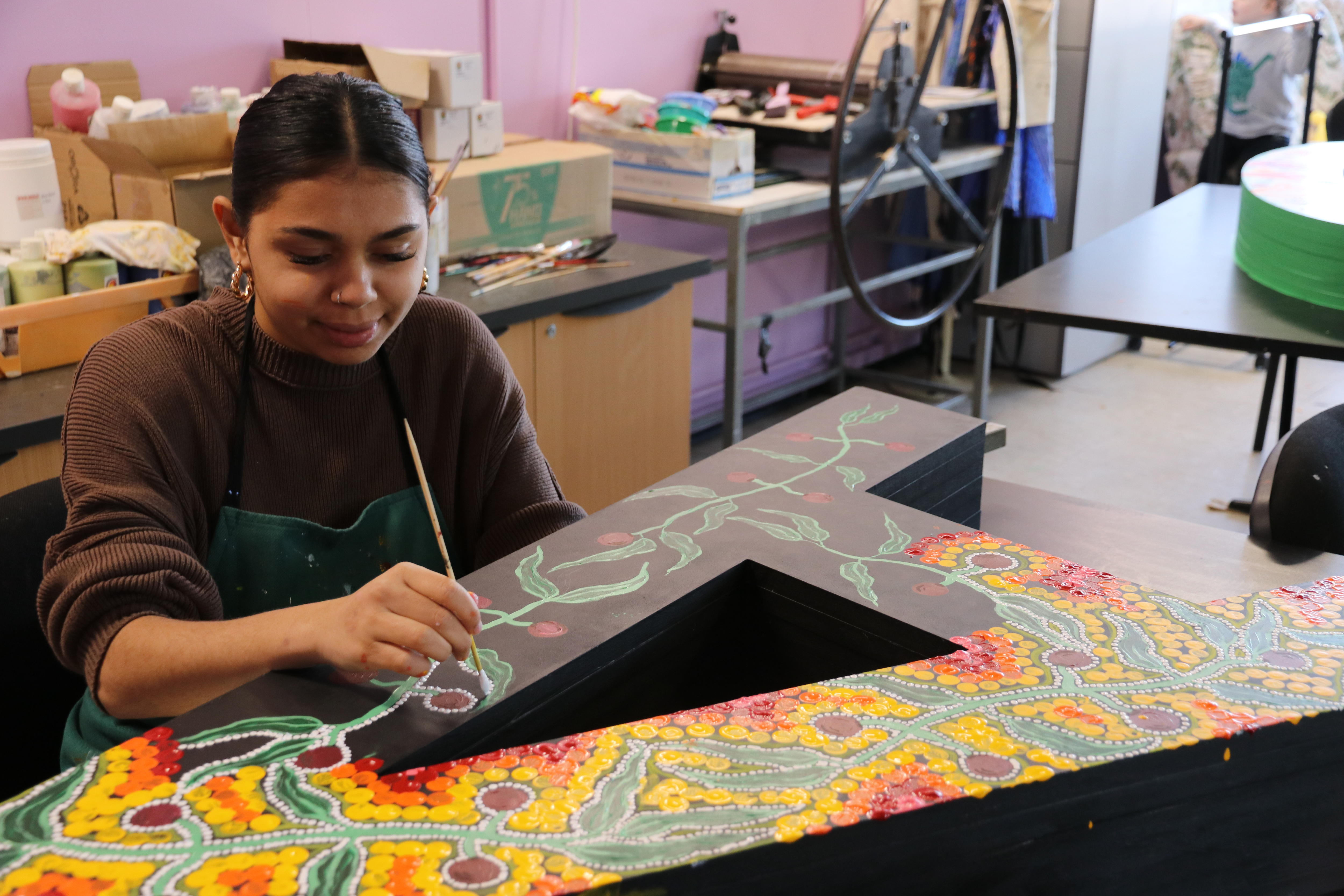 young girl paints a large letter A in dot painting