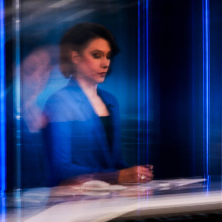 A long exposure creates a blurry and distorted image of Tamara Oudyn sitting at the ABC News desk in the studio.