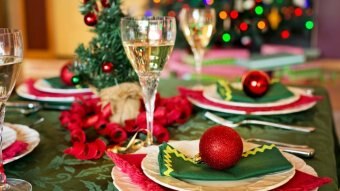 A dining table decorated with Christmas baubles, a tree and holiday-themed napkins.