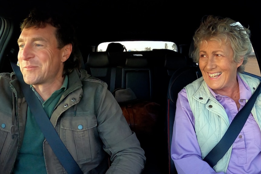 Man and woman sitting in a car and smiling. 