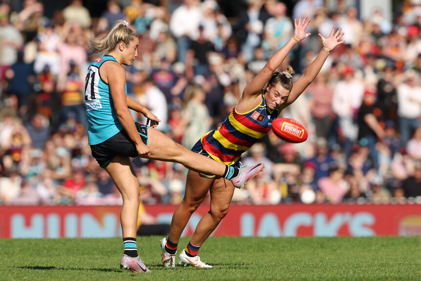 Caitlin Gould of the Crows tries to smother a kick from Amelie Borg