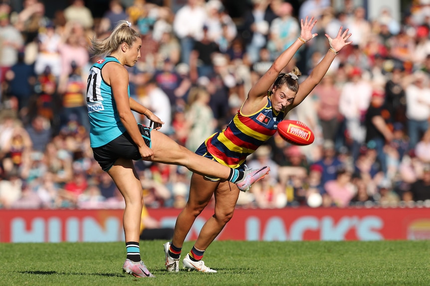 Caitlin Gould of the Crows tries to smother a kick from Amelie Borg