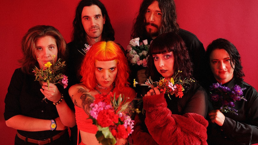 Press photo of The Maggie Pills with six member all holding flowers and looking into the camera