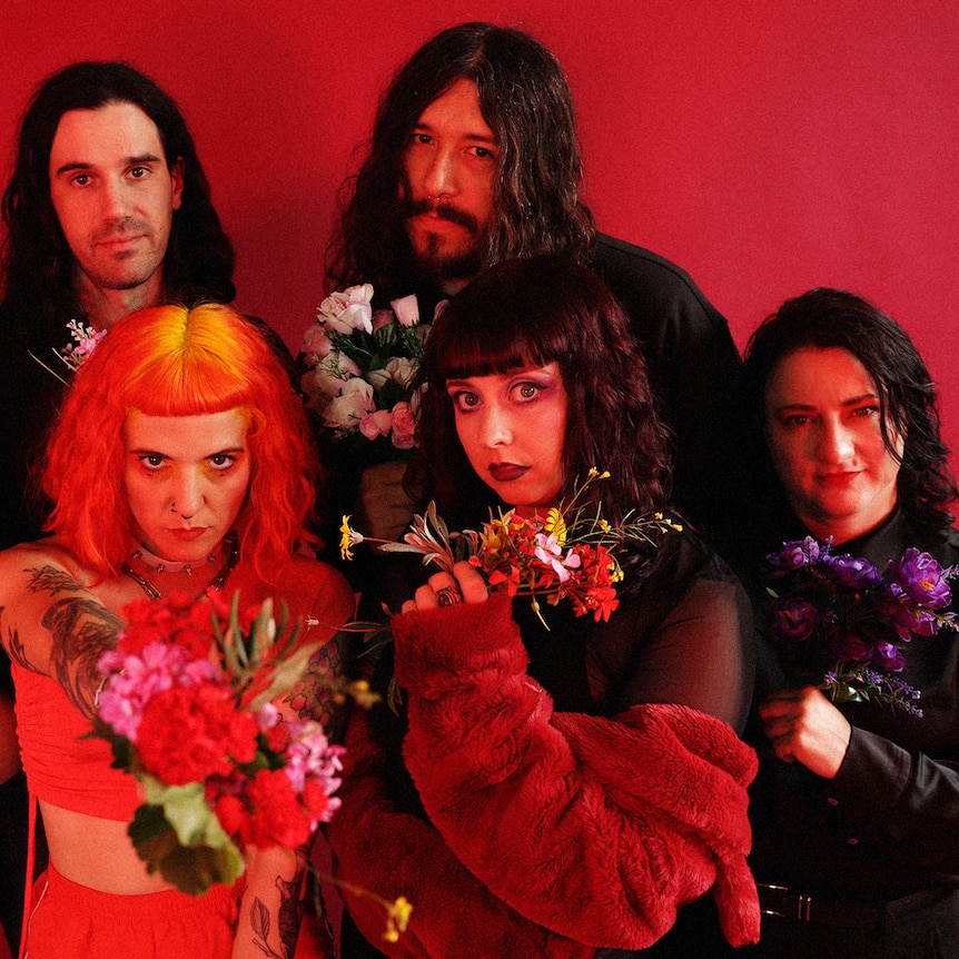Press photo of The Maggie Pills with six member all holding flowers and looking into the camera