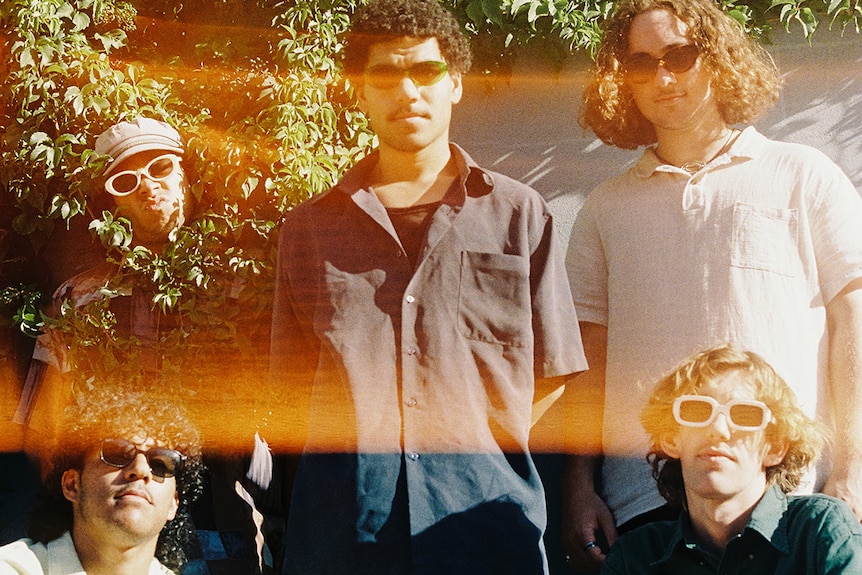 A 2022 press shot of South Summit wearing sunglasses in overexposed sunlight against a hedge fence