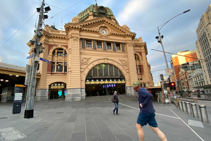 A man runs towards the steps at Flinders Street station.