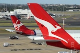 A Qantas plane parked next to a Virgin plane