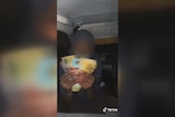 A child holding a bunch of $100 dollar notes sitting in the back of a car