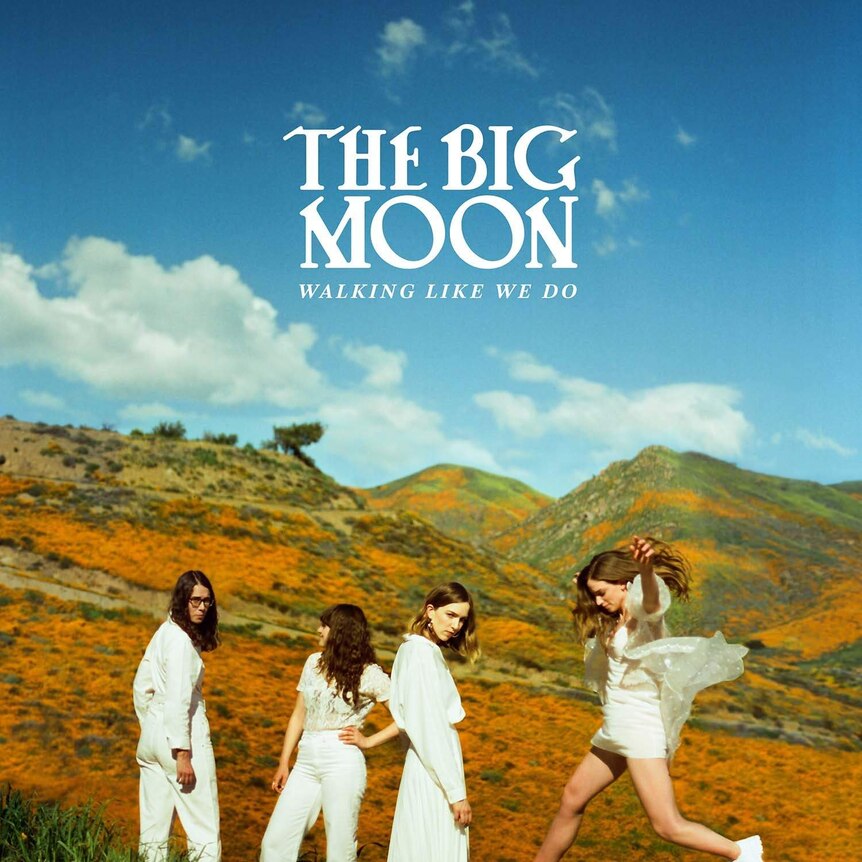 The four members of The Big Moon wearing white standing against a backdrop of hills.