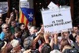 Protesters hold aloft a ballot box that reads "SPAIN, IS THIS YOUR PROBLEM?" in a crowd.