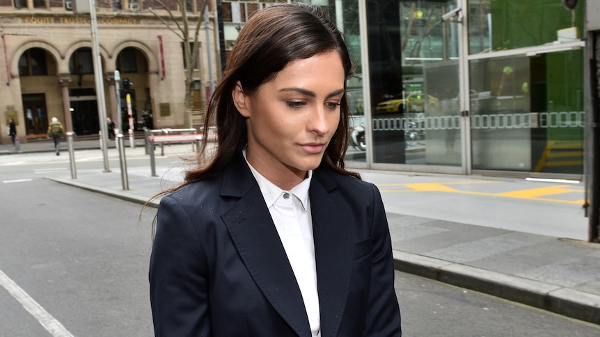 Journalist Krystal Johnson walks to court wearing a white shirt and black blazer.