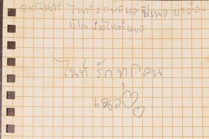 A piece of yellow paper with Thai writing in pencil.