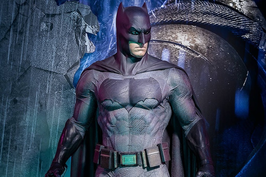 A graphic illustration of Batman, in a grey costume and dark mask