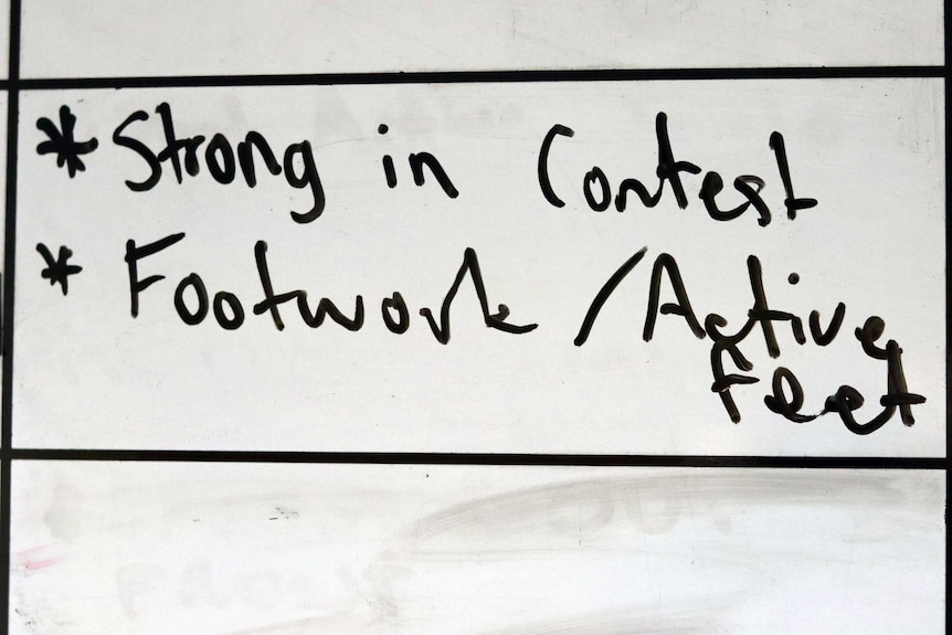 Black writing on a blackboard 'strong in contest', 'footwork active feet'