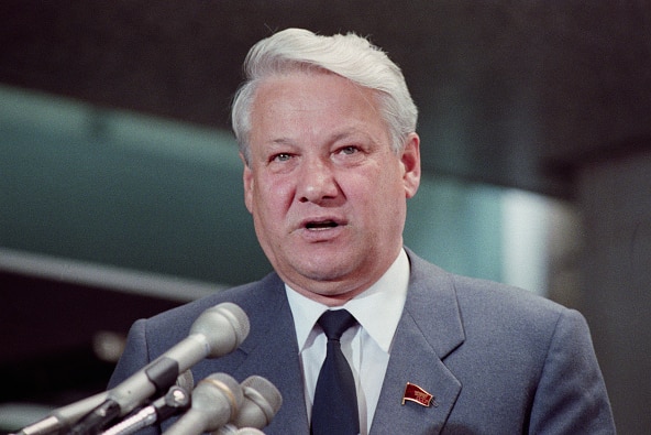 A close up of Boris Yeltsin's face, microphones from a lectern in the foreground