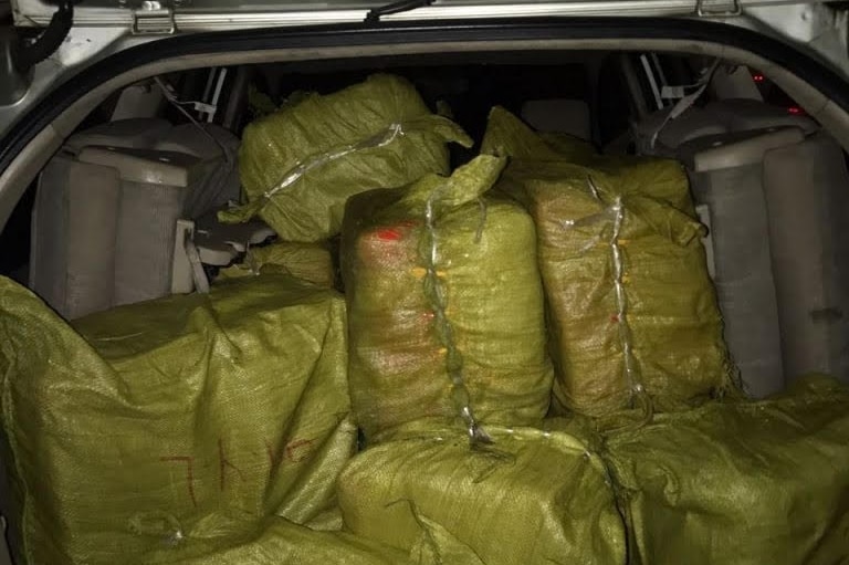 Large yellow bags of drugs sit in the open boot of a van.