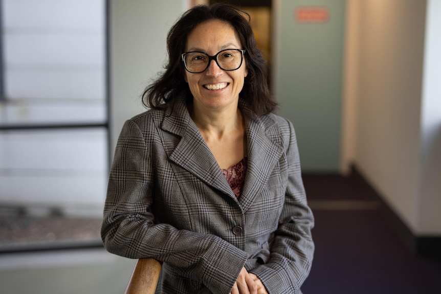 A woman with glasses and brown hair posing for the camera.