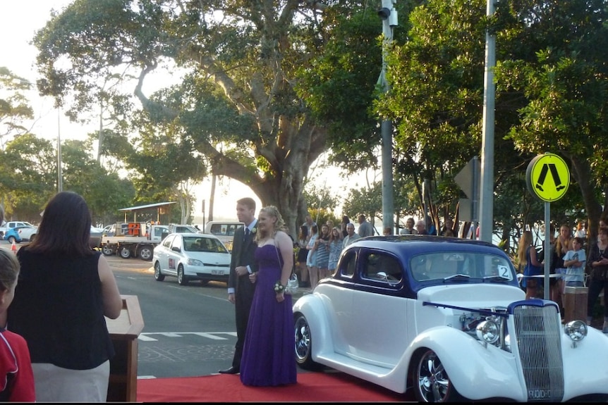 A couple on a red carpet, stepping out of a car at a formal.