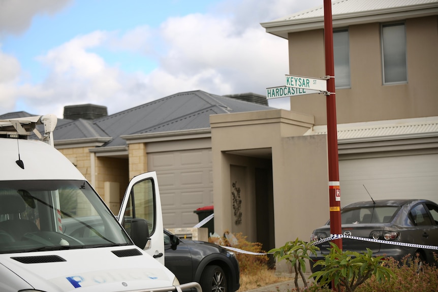 The front of a house in the daytime, with the edge of a police van visible in the foreground.