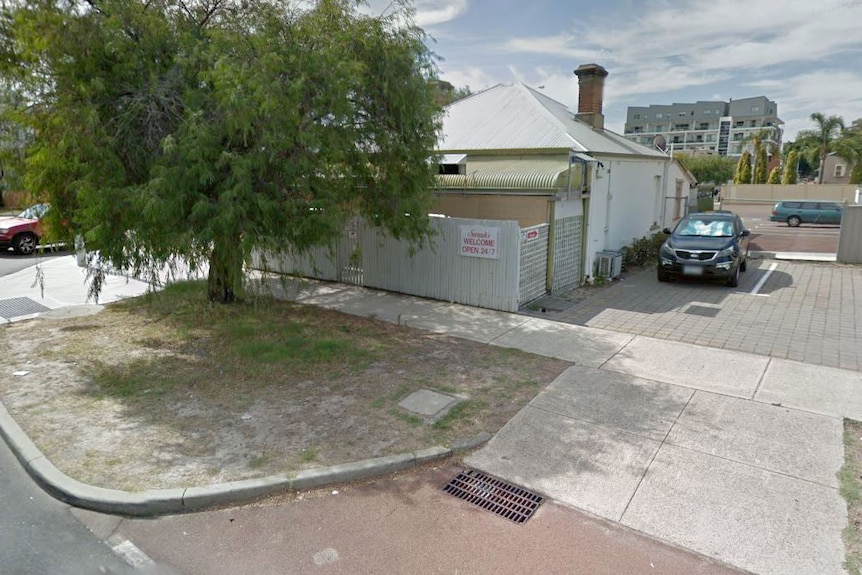 A run-down old house with a tin roof and a sign saying Sarah's welcome, open 24/7.