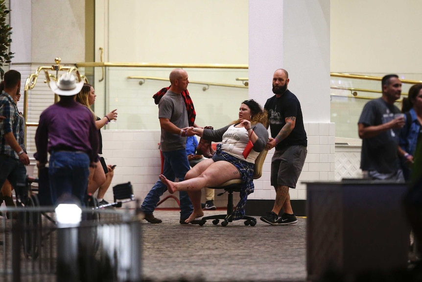 A wounded woman is moved on a rolling desk chair outside the Tropicana