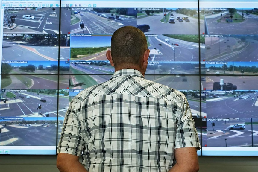 A man staring at a large screen of CCTV cameras.