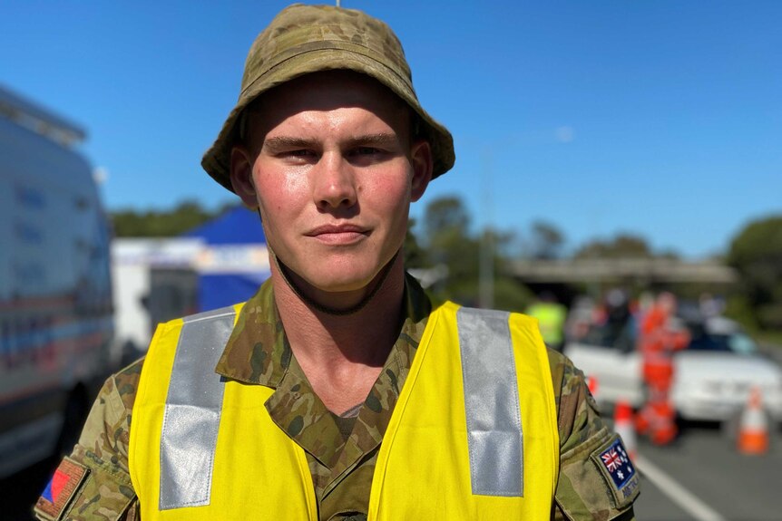 A man wearing army uniform and a high viz vest