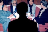 A man's shadow falls on a photo of Deng Xiaoping sitting opposite Margaret Thatcher in a meeting.