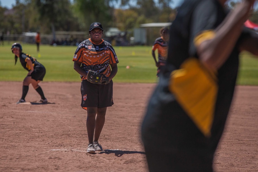 A young Indigenous woman prepares to pitch a softball.