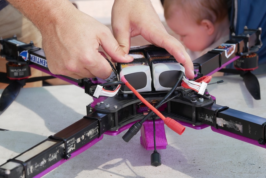 close up of two hands moving a part on top of a large purple drone