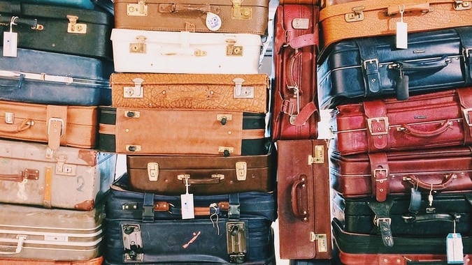 A large pile of colourful suitcases filling entire frame of image. Squashed on top of each other