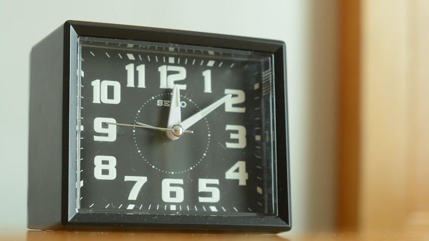Close-up shot of a small, black Seiko analogue alarm clock with white numbers.