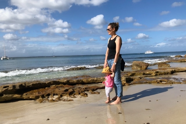 Leonie and her child walk on the beach.
