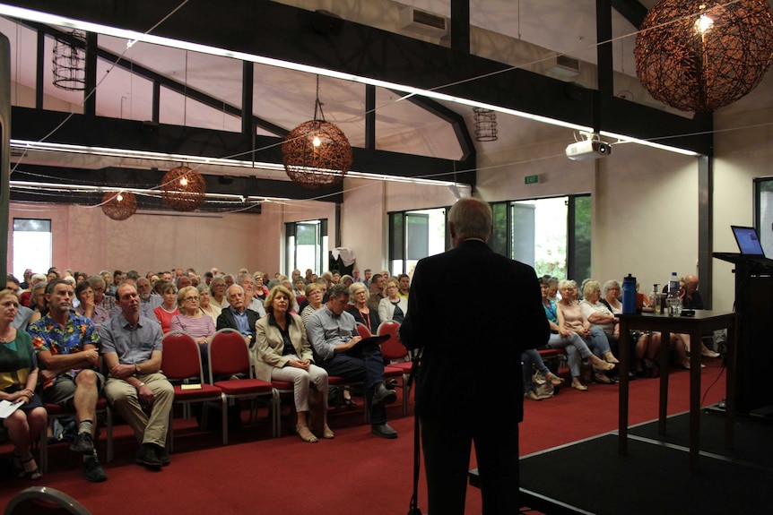 The Alpine mayor addresses a room full of people.