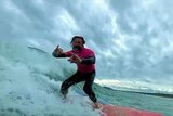 Man surfing a wave and smiling at the camer