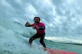 Man surfing a wave and smiling at the camer