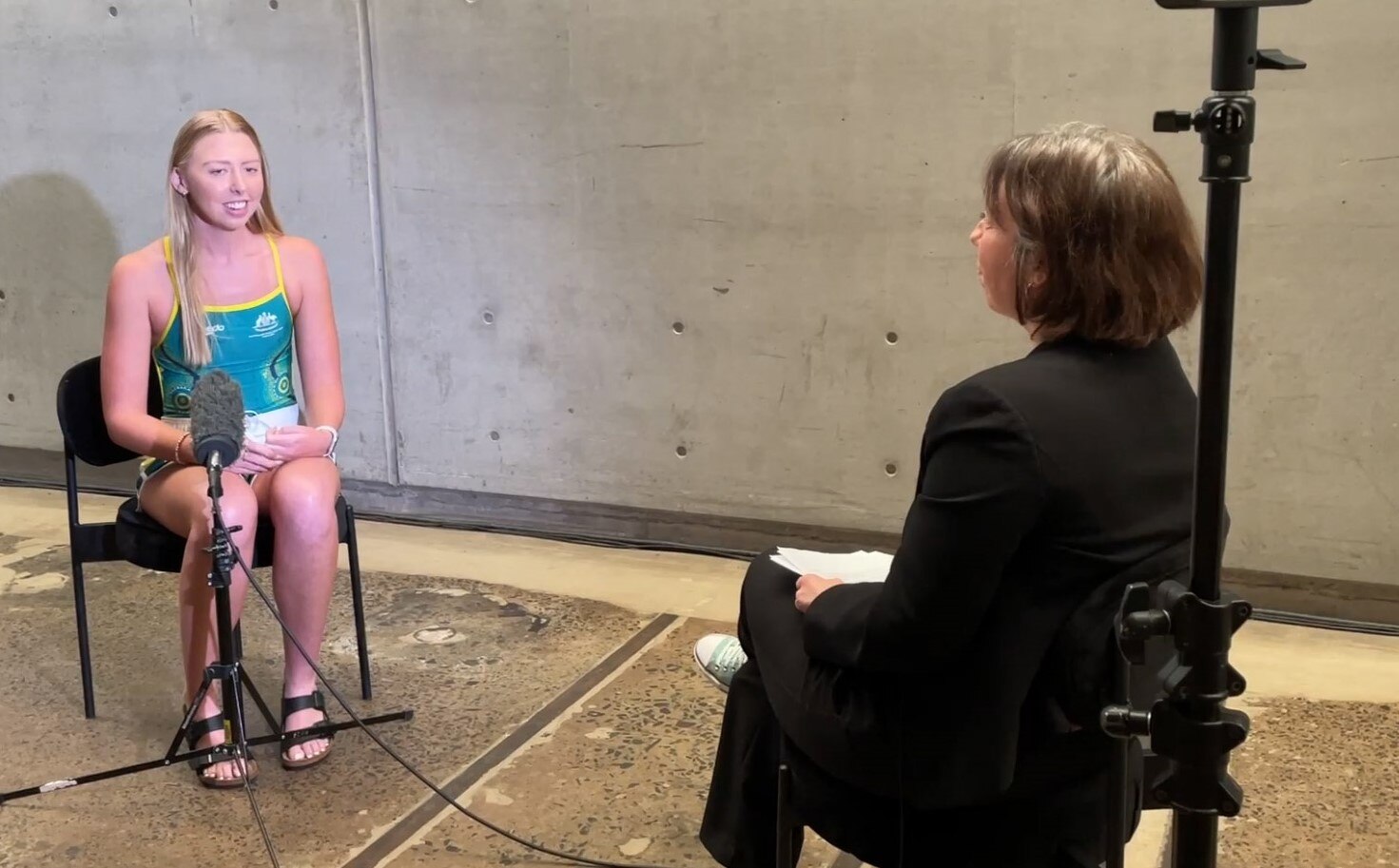 Paralympian Lakeisha Patterson in a one piece swimming costume, being interviewed by Elizabeth Wright.