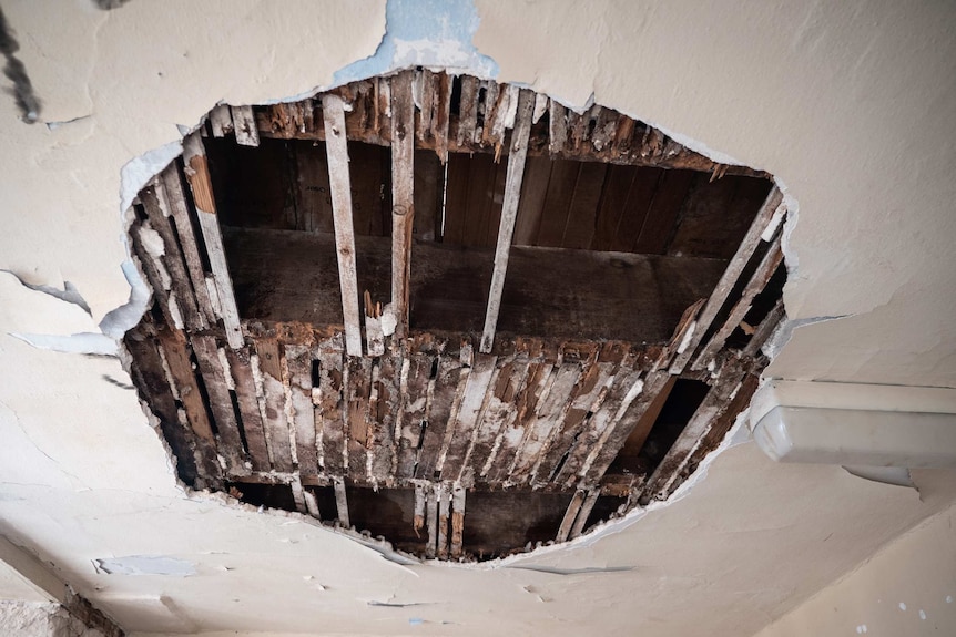 A lathe and plaster ceiling space broken open to show space and floorboards above,