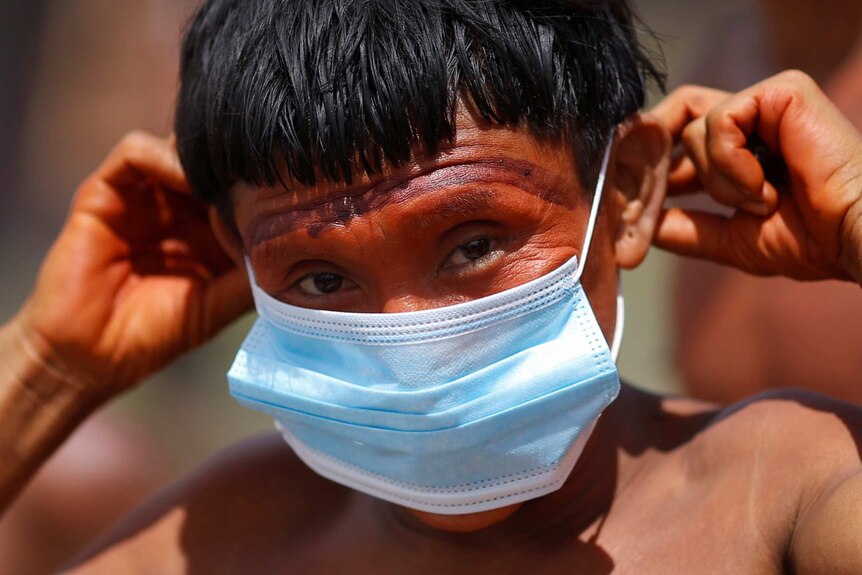 A man from the indigenous Yanomami ethnic group holds a protective mask to his face