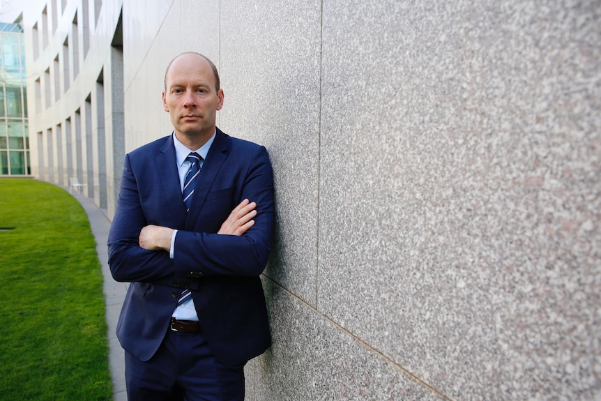 Geoff Evans leans against a wall with his arms crossed.