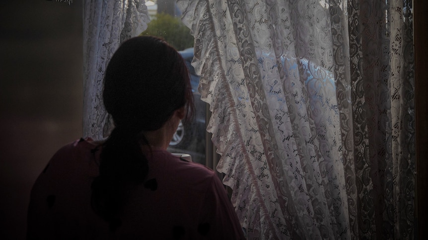 Unidentified woman looking out of her window.