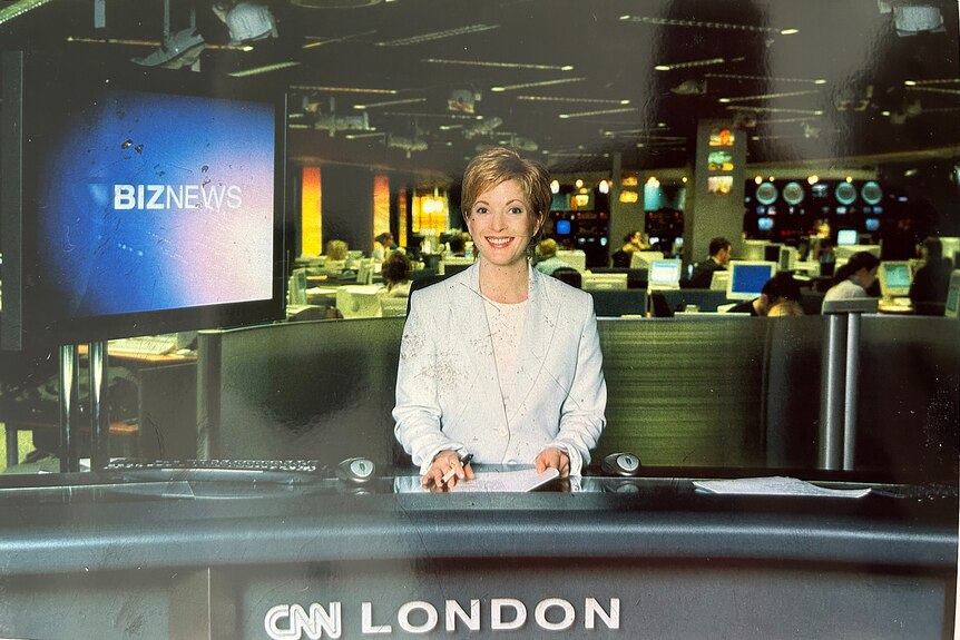 a woman sitting behind a news desk looking at the camera