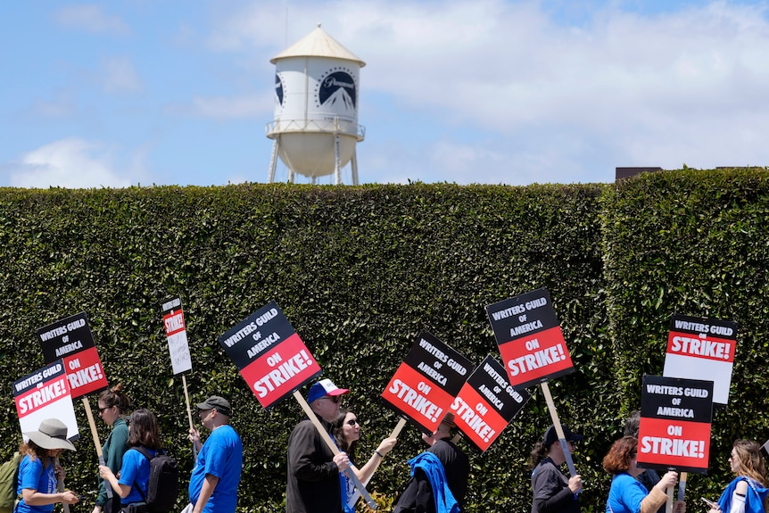 Strikers hold placards in front of paramount studios water tower 