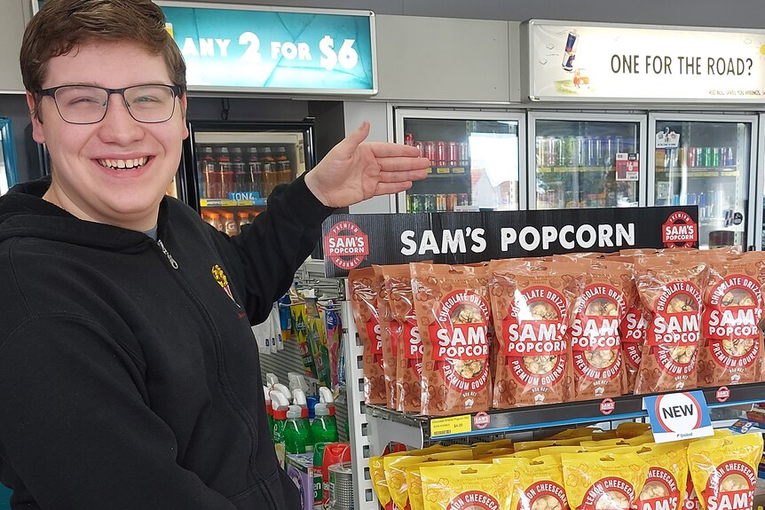 Sam smiles as he shows off the display of his popcorn in a petrol station store.
