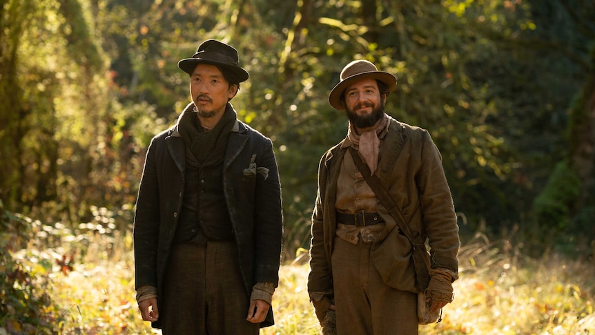 A still from the film First Cow showing two men with hats and beards in a forest setting.