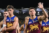 Brisbane Lions walk off the field after an AFL game.