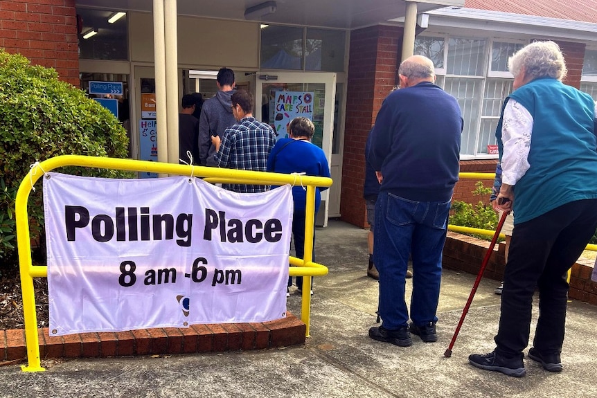 A sign reading polling place, and a line of people coming out of a building