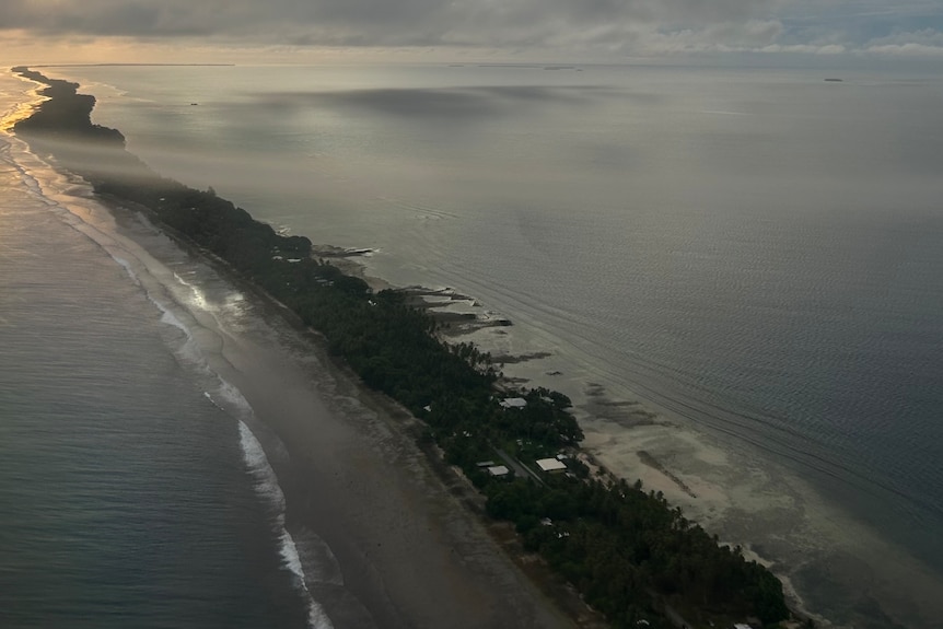 A thin strip of land in the ocean at sunset