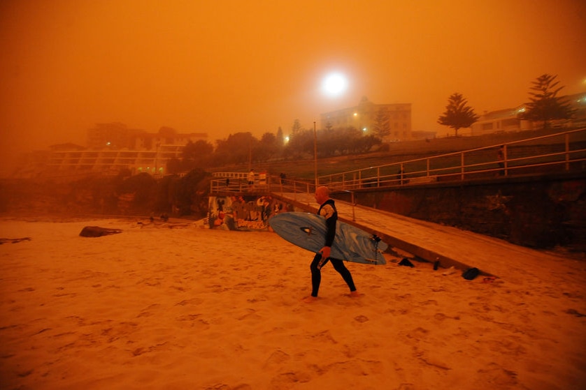 A surfer on a beach, with everything coloured in an orange glow.